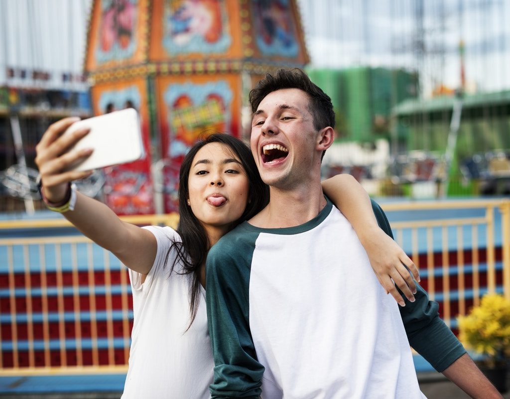 Two Gen Z individuals take a selfie with a smartphone