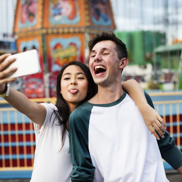 Two Gen Z individuals take a selfie with a smartphone